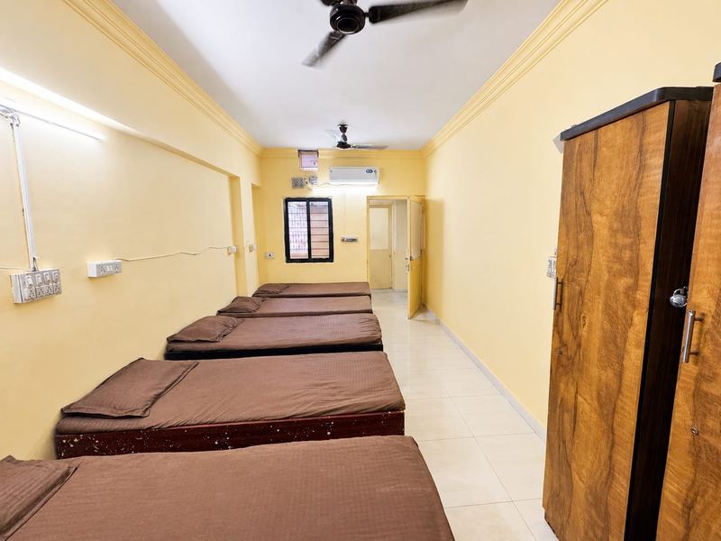 AC 5-sharing room at Jay Ambe Boys PG, with five made beds, wardrobes and the attached bathroom door
